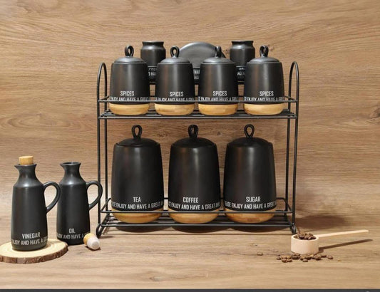 طقم توابل أسود مع رف طابقين وعبوات شاي وقهوة وسكر وزجاجات زيت وخل ومغرفة خشبية